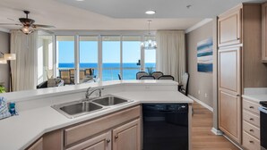 A modern kitchen with a large island, a dishwasher, and a view of the ocean. - 🌊Silver Beach 603E | Beach Front | Upscale + Disc. Beach Service (Destin)