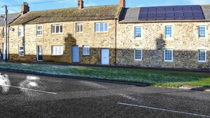 A row of stone houses with a paved road in front.