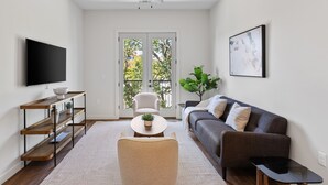 A modern living room with a flat-screen TV, a sofa, a coffee table, and a ceiling fan.