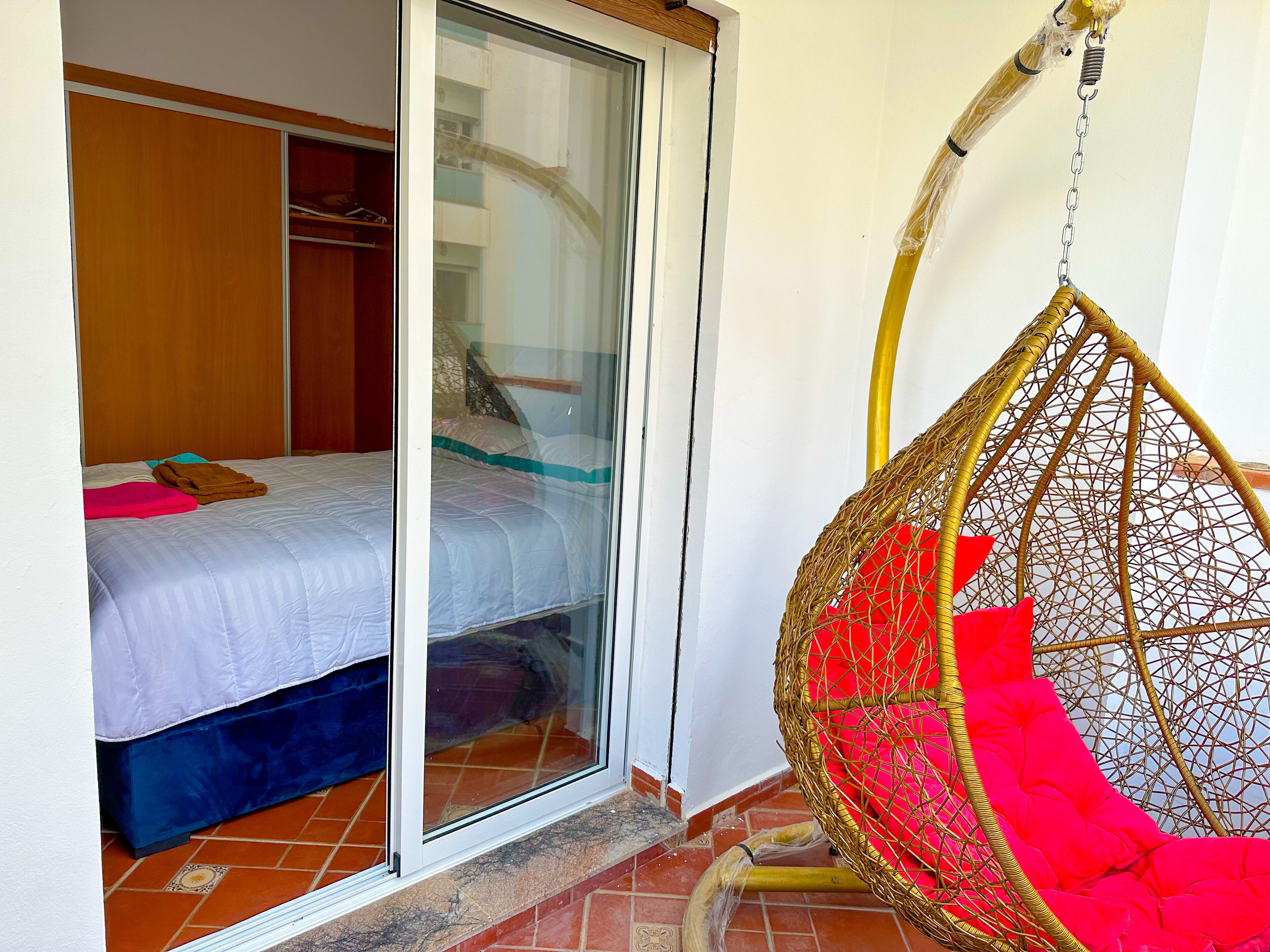 Een slaapkamer met een bed, een kledingkast en een hangstoel.
