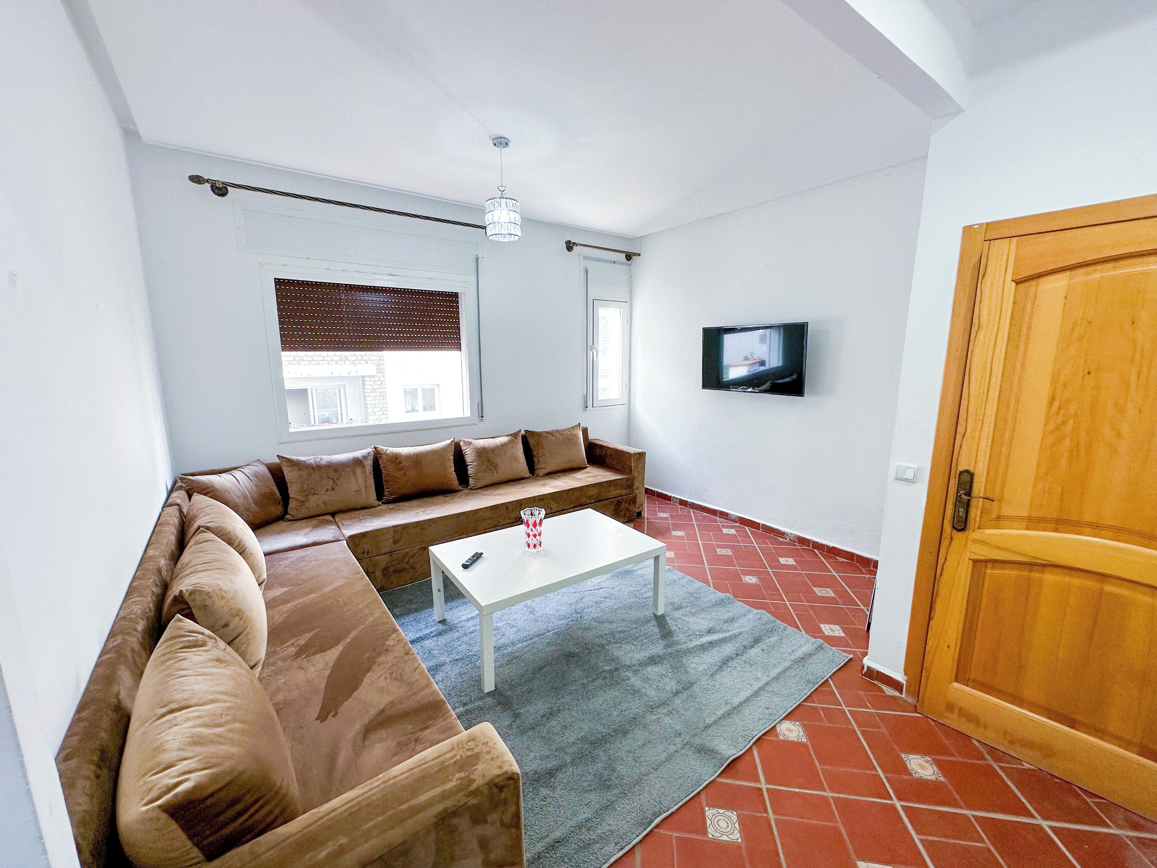 A living room with a sofa, a coffee table, a TV, and a wooden door.