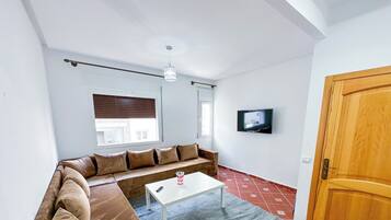 A living room with a sofa, a coffee table, a TV, and a wooden door.