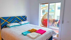 A bedroom with a bed, a window, and a view of buildings outside. - Apartment with pool direct access to sea (Oued Laou)