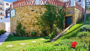 A stone wall with a wooden fence, a door, and a small garden area with grass and plants. - Apartment with pool direct access to sea (Oued Laou)