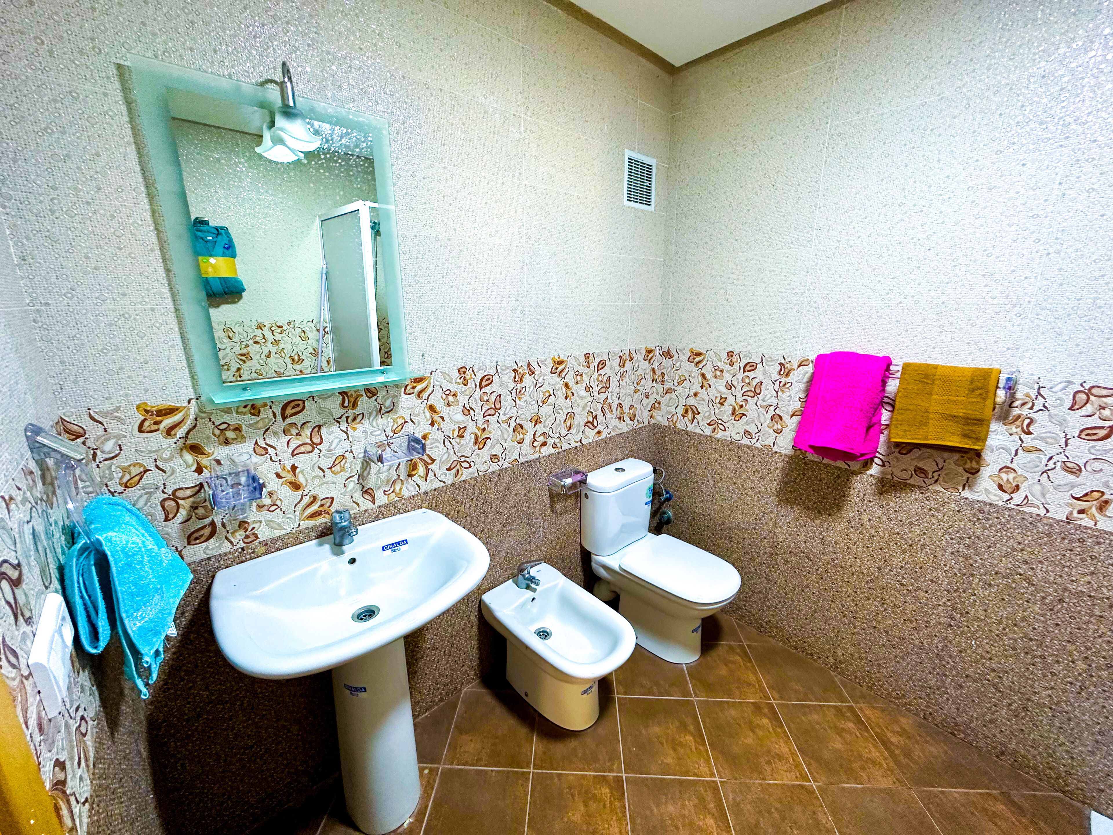 A bathroom with a sink, toilet, and mirror.
