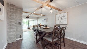 Een eethoek met een houten tafel en stoelen, een accentmuur van baksteen en hanglampen.