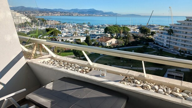 A balcony with a view of a marina, buildings, and mountains.
