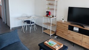 A modern living room with a sofa, a dining table with chairs, a TV, and a wooden cabinet.