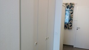A hallway with a white door at the end, a patterned curtain, and a tiled floor.