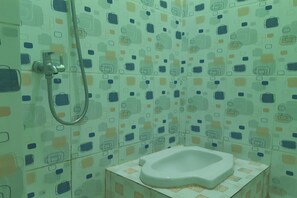 A bathroom with a toilet, shower, and a wall with a geometric tile pattern. - Hotel O Es Em Je Residence (Medan)