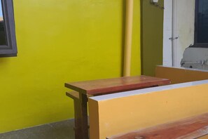 A yellow wall with a wooden bench and a window. - Hotel O Es Em Je Residence (Medan)