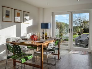 A dining area with a wooden table, green chairs, and a view of the garden through glass doors. - 3 bedroom accommodation in Leitholm, near Coldstream (Leitholm, near Coldstream)