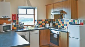 A compact kitchen with wooden cabinets, a microwave, a dishwasher, and a stove.