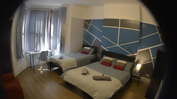 A modern hotel room with two beds, a desk, and a chair. - Kensington Guest House Liverpool (Liverpool)