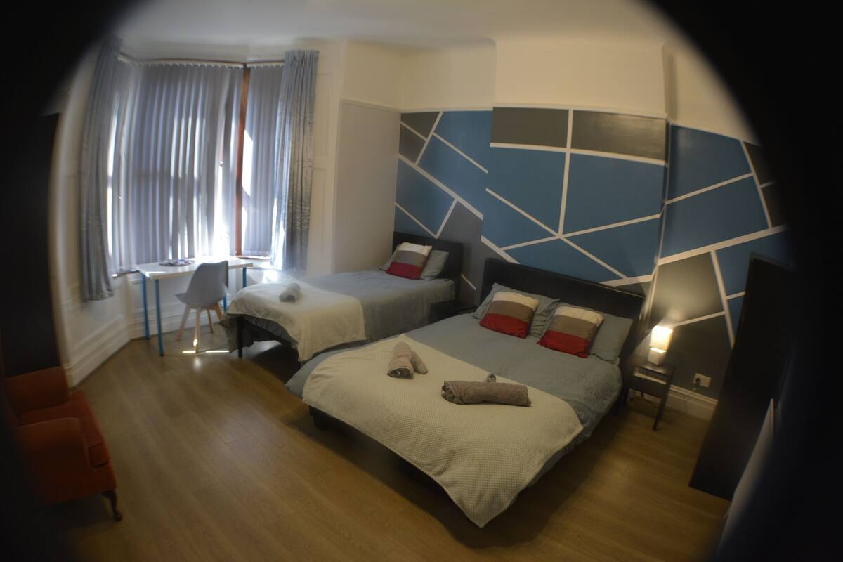 A modern hotel room with two beds, a desk, and a chair.