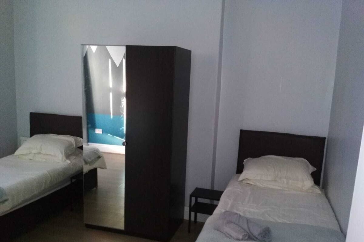 A room with two single beds, a small table, and a wardrobe.