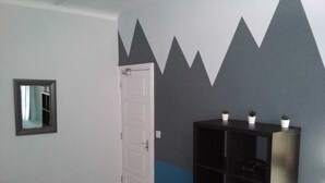 A room with a door, a small mirror, and a black shelving unit against a wall with a geometric pattern. - Kensington Guest House Liverpool (Liverpool)