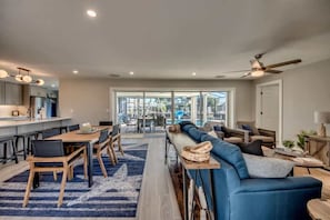 A modern kitchen with a dining area, a blue sofa, and a ceiling fan.