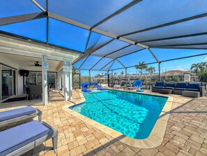 A covered swimming pool with lounge chairs and a patio area.