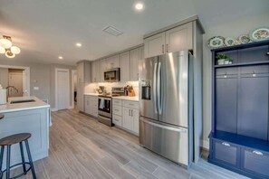 A modern kitchen with stainless steel appliances, a central island, and a built-in cabinet with decorative plates.