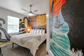A bedroom with a bed, a ceiling fan, a map mural, and a large ocean-themed painting. - 8BR Near Disney•6 Kings•Heated Pool•Star Wars (Davenport)