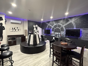 A room with a Star Wars theme, including a wall mural, a large screen, and a seating area with a table and chairs. - 8BR Near Disney•6 Kings•Heated Pool•Star Wars (Davenport)