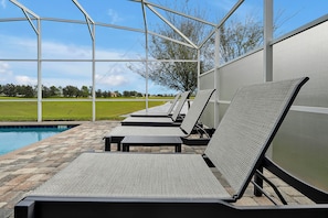 A poolside area with lounge chairs and a covered patio. - 8BR Near Disney•6 Kings•Heated Pool•Star Wars (Davenport)