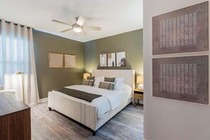 Ein Schlafzimmer mit Bett, Nachttischen, Deckenventilator und Bildern an den Wänden.