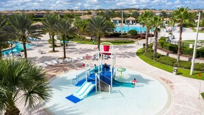 Un parc aquatique doté d’une structure de jeux centrale, de plusieurs piscines et entouré de palmiers.