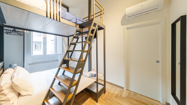 A dorm-style room with a bunk bed, a wooden ladder, a window, and an air conditioning unit. - Central Station Apts by Wonderful Italy - Cetara (Naples)