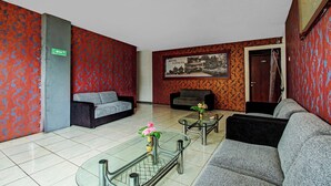 Un vestíbulo de hotel con paredes con diseño, una recepción, sofás y una mesa de centro con flores.