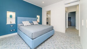 Un dormitorio con cama, mesita de noche y estante en la pared.