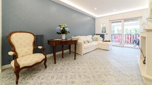 Una habitación con suelo estampado, un sofá blanco, una silla de madera y una mesa con un jarrón de flores.