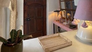 An arched doorway leading to a room with a wooden door, a hanging lamp, a small table with a lamp, and a potted plant. - Riad Privado no Coração da Medina - Dar el Bacha (Marrakech)