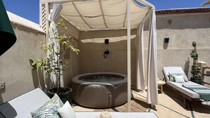 A rooftop patio with a hot tub, lounge chairs, and a canopy. - Riad Privado no Coração da Medina - Dar el Bacha (Marrakech)