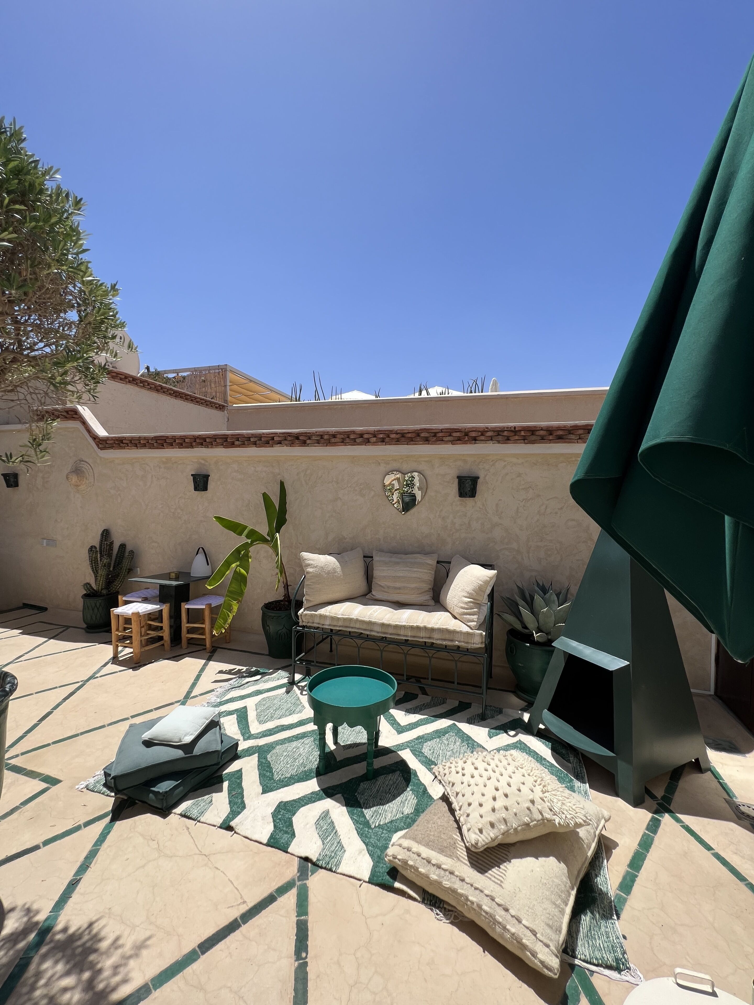 A patio area with a sofa, chairs, a small table, and potted plants.
