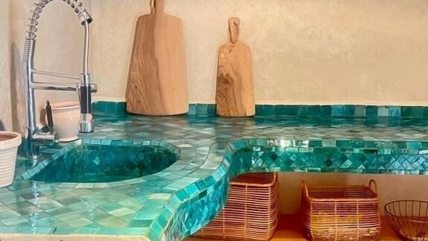 A kitchen with a blue mosaic backsplash, wooden shelves, and a gas stove. - Riad Privado no Coração da Medina - Dar el Bacha (Marrakech)