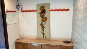 A hallway with a wooden bench, a wall-mounted light fixture, and a decorative sunflower painting.