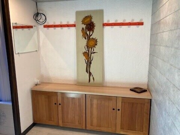 A hallway with a wooden bench, a wall-mounted light fixture, and a decorative sunflower painting.