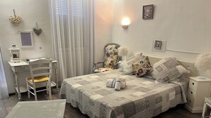 Un dormitorio ordenado con cama, mesitas de noche, un escritorio y una silla.