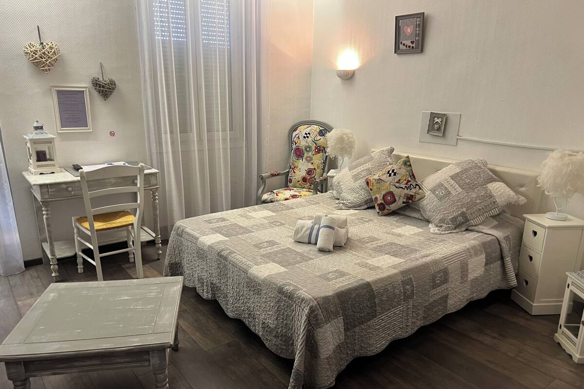 A neatly arranged bedroom with a bed, bedside tables, a desk, and a chair.