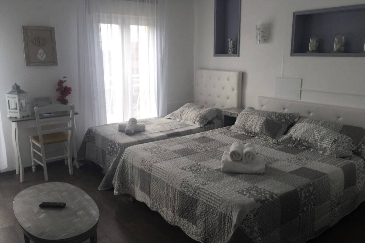 A bedroom with two beds, a desk, and a chair.