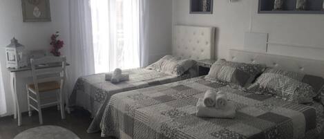 A bedroom with two beds, a desk, and a chair.