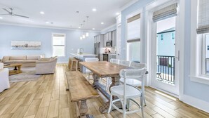 A spacious living room with a wooden dining table, white chairs, and a beige sofa. - Sea Glass: Free golf cart, 2min to beach, Heated pool steps away, Bunk rooms (Miramar Beach)