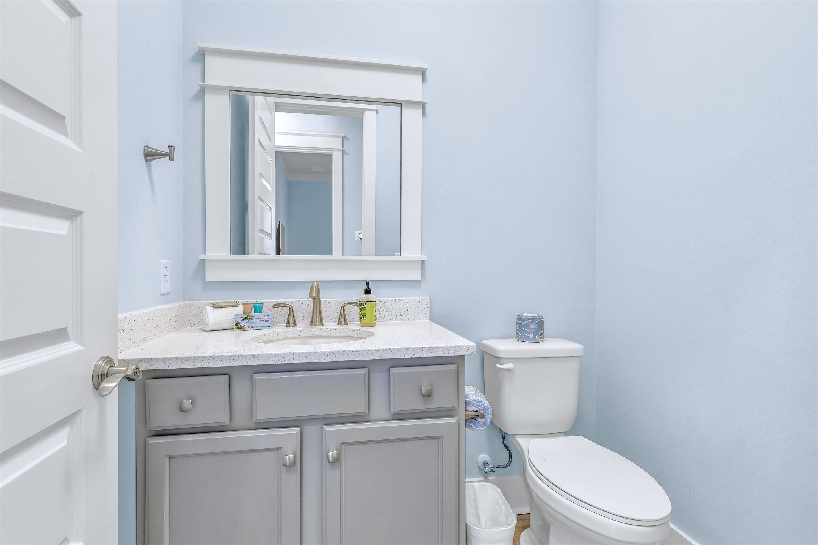 A bathroom with a white sink, a mirror above it, and a toilet.
