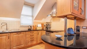 Una cocina moderna con armarios de madera, encimera negra y una ventana con persianas.