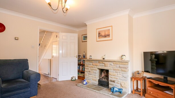 A living room with a fireplace, a television, a sofa, and a bookshelf. - 1 Crowlands Cottages (Holt)