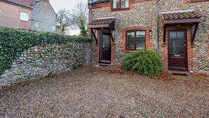 A stone house with a gravel driveway, a stone wall, and a wooden fence. - 1 Crowlands Cottages (Holt)