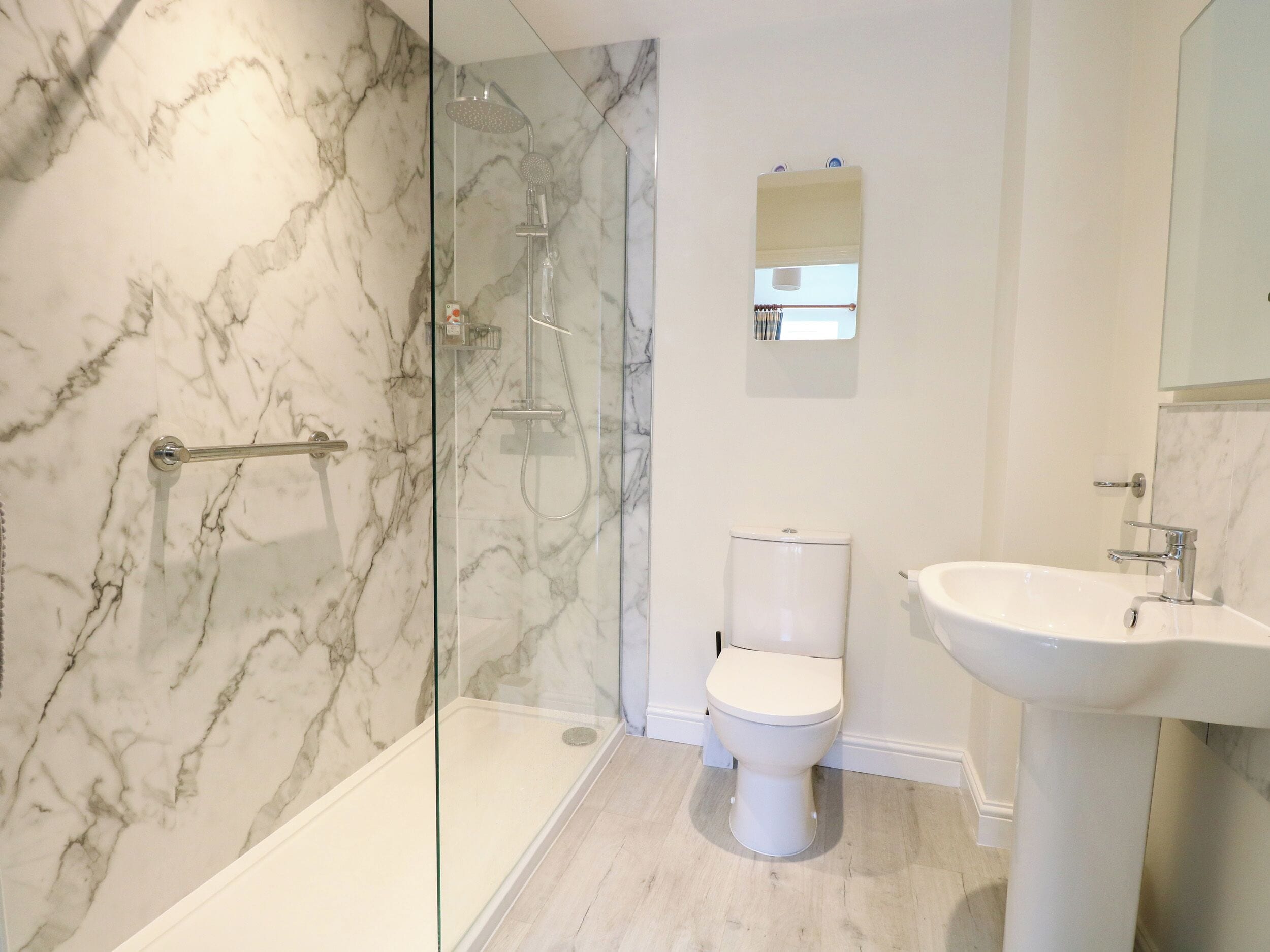 A bathroom with a glass-enclosed shower, a toilet, and a sink.