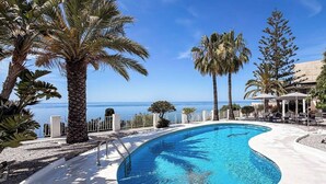 A swimming pool with a curved edge, surrounded by palm trees and a view of the ocean. - Villa Sofia - Four Bedroom Villa, Sleeps 10 (Salobreña)